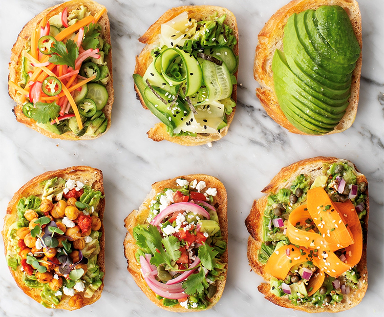 6 slices of bread with various toppings like avocado, cucumber, carrots and other vegetables. 