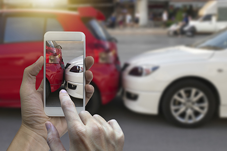 POV short of someone taking a photo of a white car crashed into the back of a red car