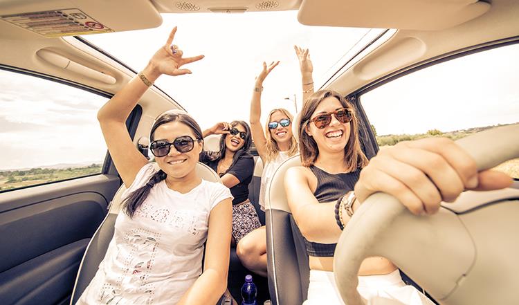Group of girls in car with arms in the air