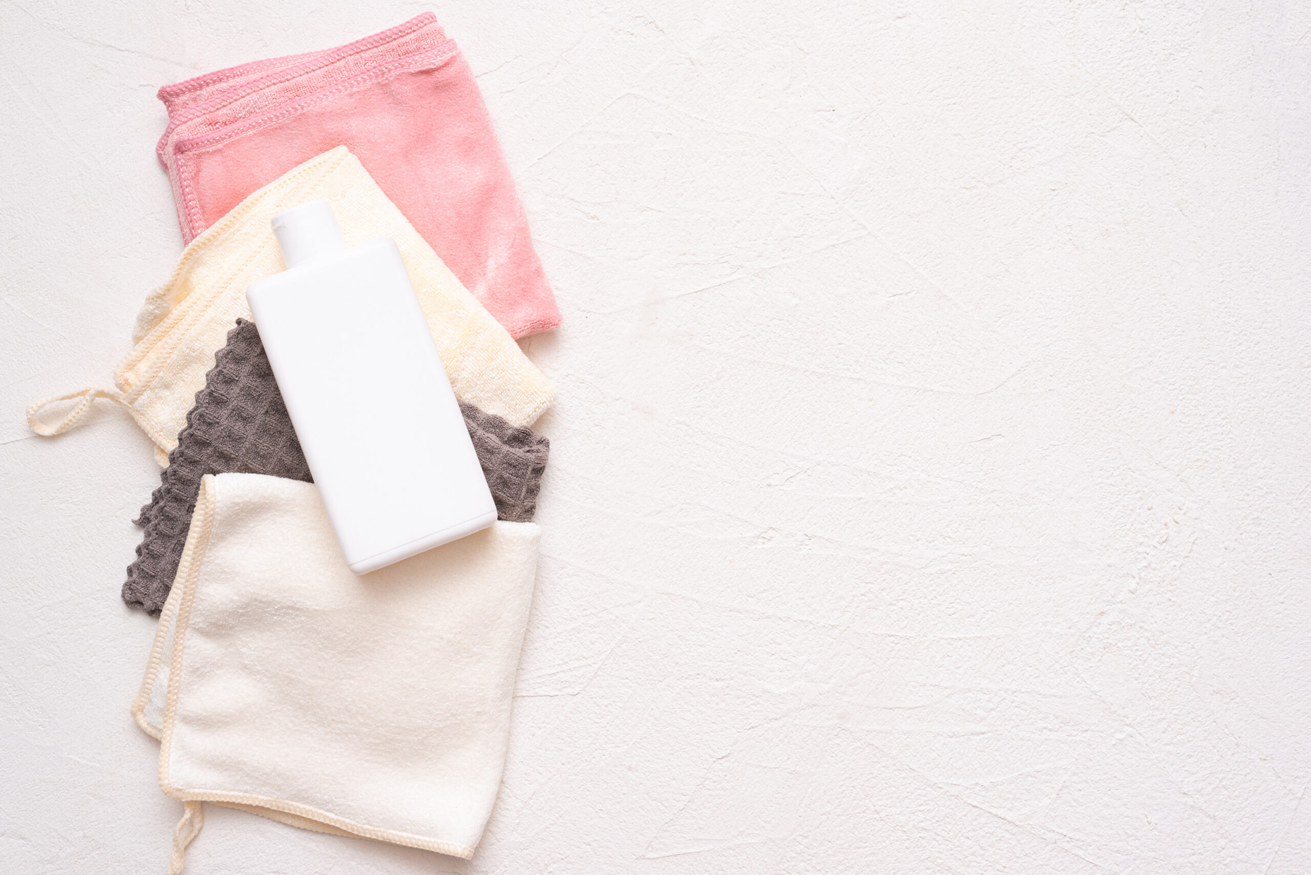 5 Sustainable Household Swaps to Make Today. Dish cloths and detergent bottle on white flat lay background.