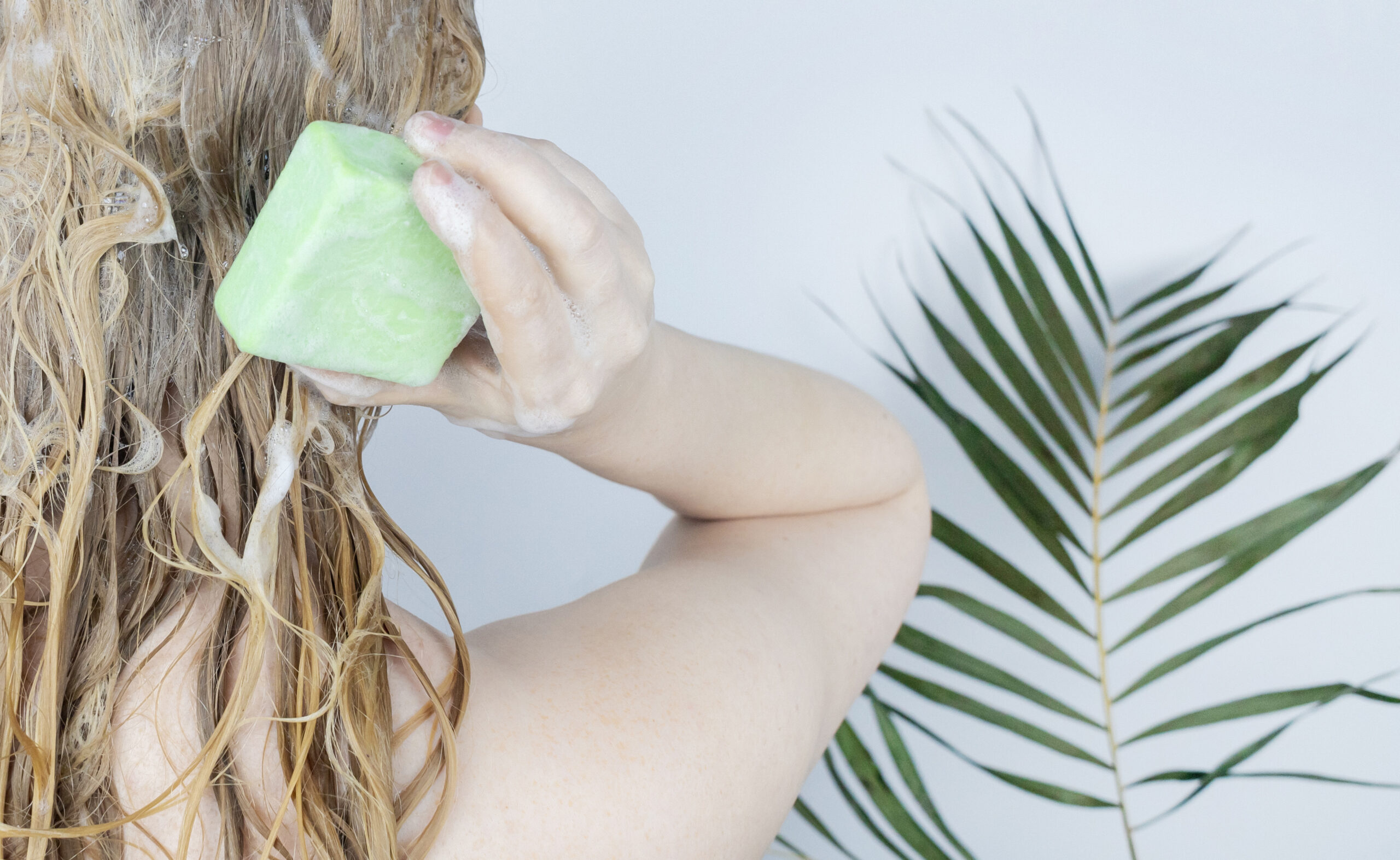 5 Sustainable Household Swaps to Make Today. Close-up of a blonde girl in the bathroom, which lathers her hair with dry shampoo. 