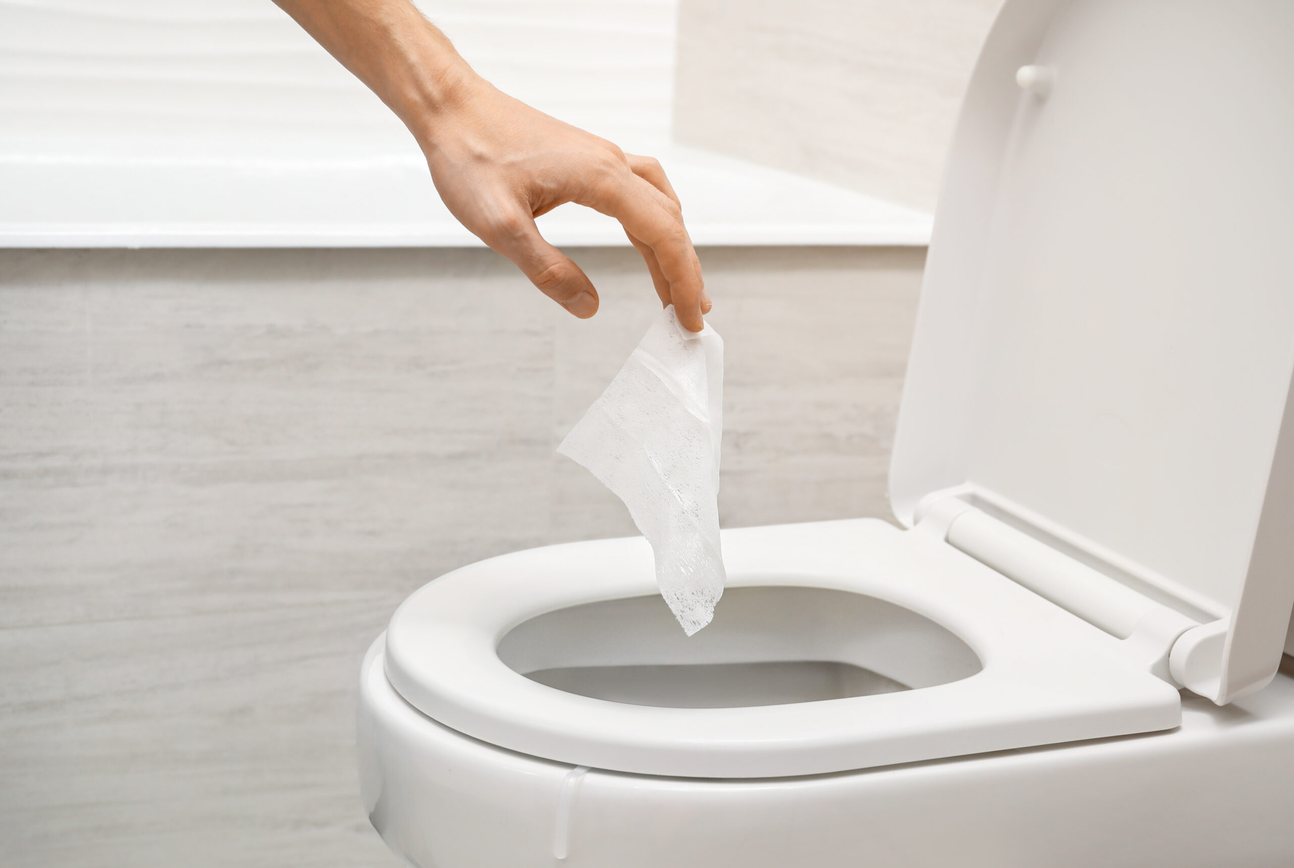 Hand throwing out toilet sheet in bowl