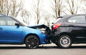 Blue car with a dented in bonnet after crashing into a black car in front of it