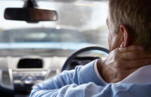 Man holding his neck with whiplash in a car