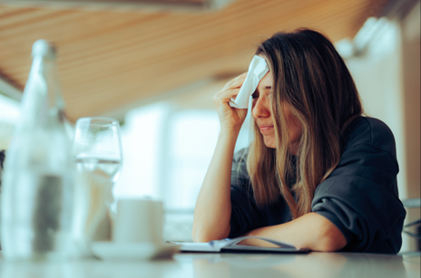 An upset female with dark hair holding a tissue