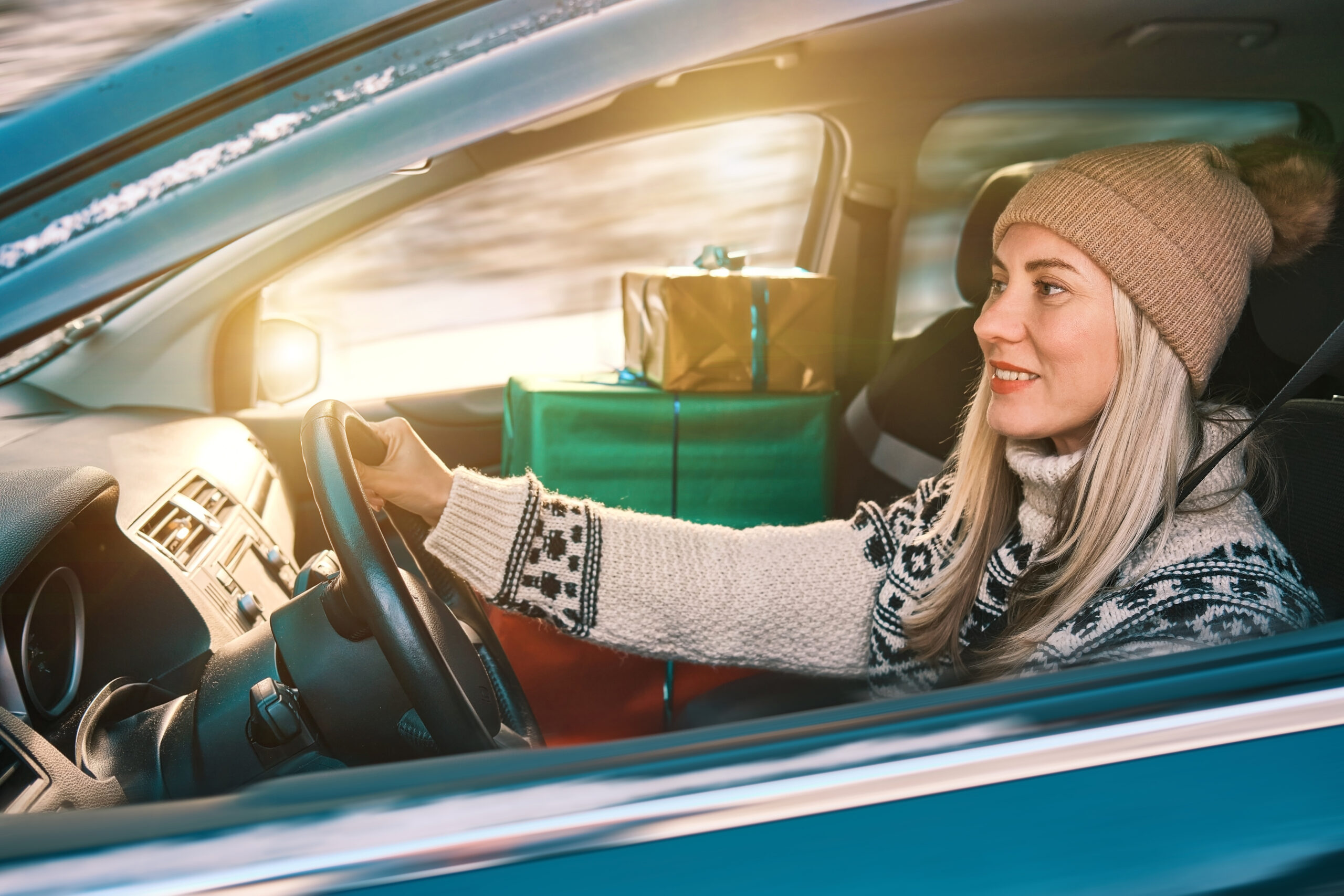 Woman in car with presents driving home for Christmas 