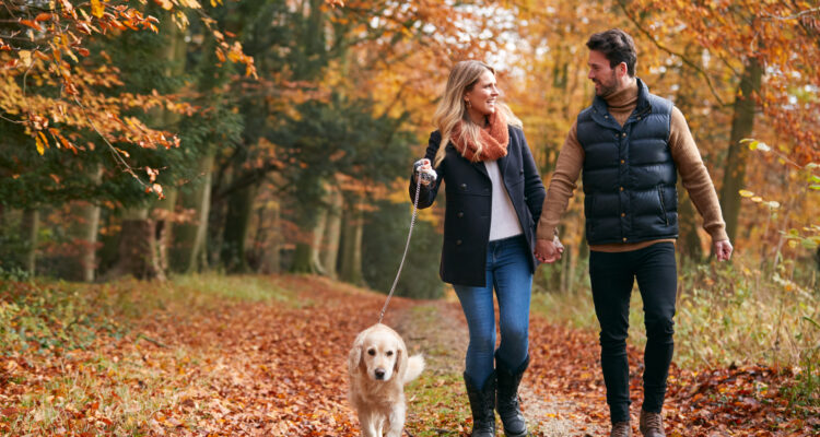 Couple walking outdoors in Autumn with their dog