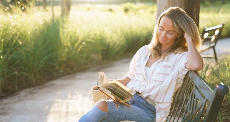 Lady sitting on a bench reading book