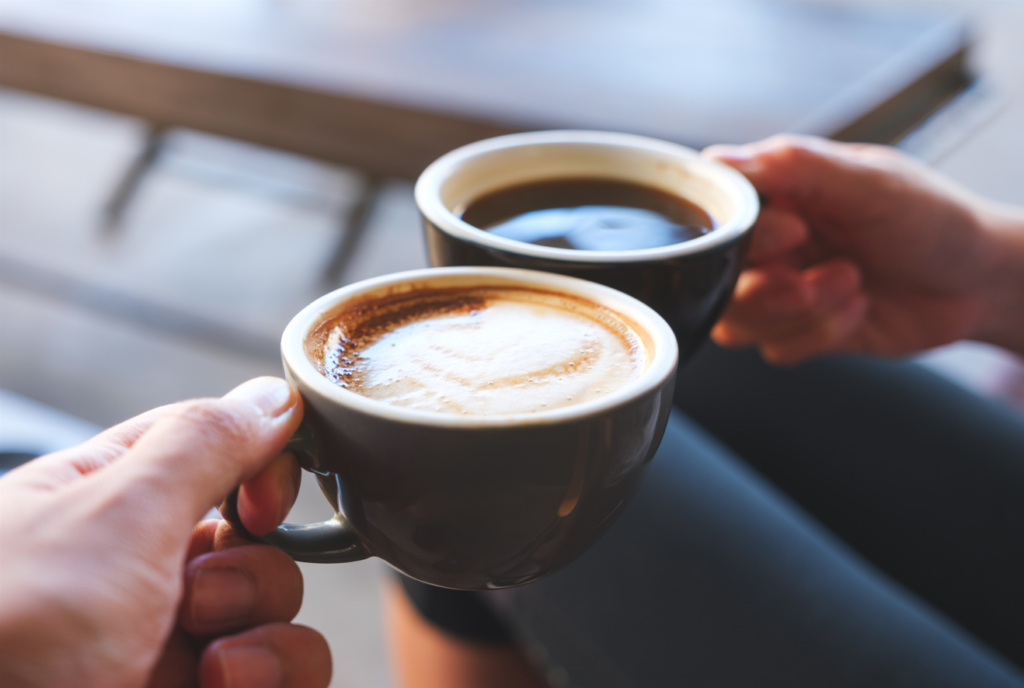 Two people clinking coffee cups